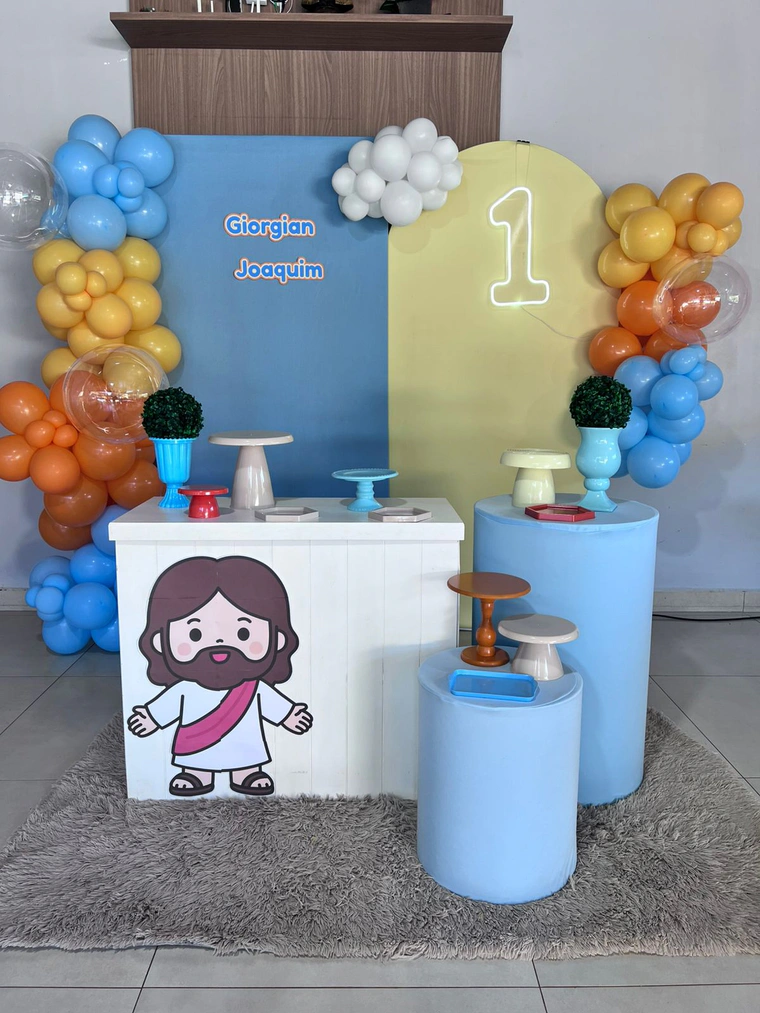 Painel azul e amarelo com desenho religioso, balões coloridos e balcão branco