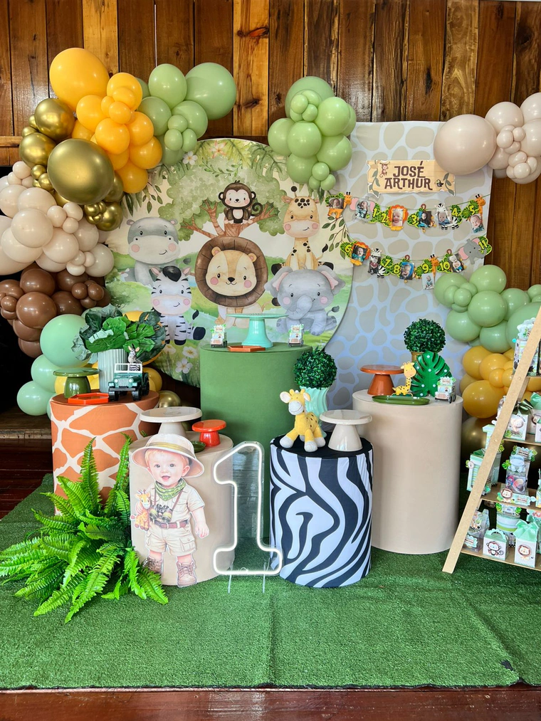 Cenário de safari com bichinhos, balões em verde, marrom e dourado, e cilindros de zebra e girafa